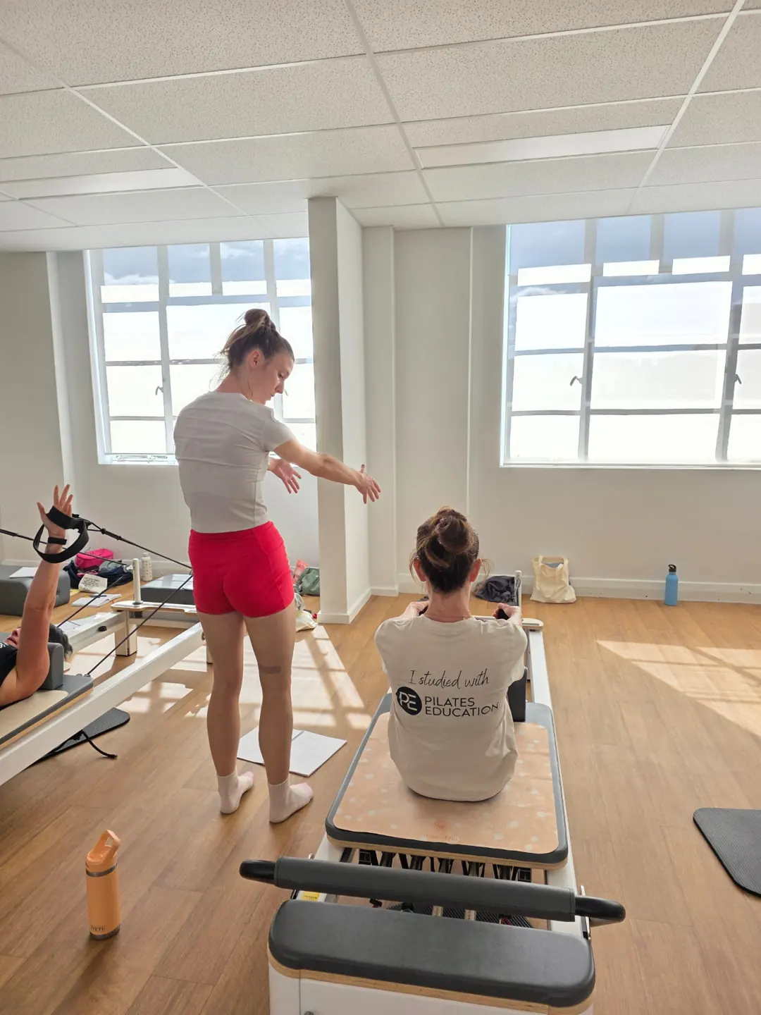 Educator cueing a student seated on the reformer, teacher training Pilates Wollongong